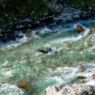 Kobarid, Slovenya - 17 Ekim 2021: Slovenya 'nın kuzeyindeki dağlardaki Soca Nehri' nin berrak turkuaz sularında yüzen kanocu.