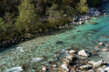 Kobarid, Slovenya - 17 Ekim 2021: Slovenya 'nın kuzeyindeki dağlardaki Soca Nehri' nin berrak turkuaz sularında yüzen kanocu.