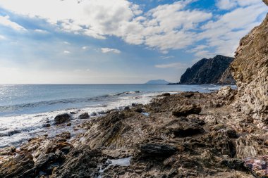 Önünde kayalar ve gelgit havuzları olan vahşi bir kıyı şeridi.
