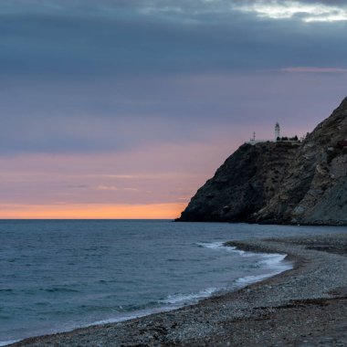 A view of La Chucha Beach and the lighthouse of Cabo Sacratif in Andalusia at asunset clipart