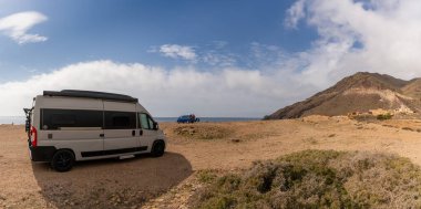 Cabo de Gata, İspanya - 3 Mart 2022: Endülüs 'ün vahşi sahillerindeki kayalık bir plaja kamp araçları park etti.