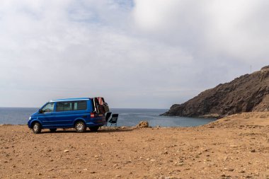 Cabo de Gata, İspanya - 3 Mart 2022: Endülüs 'ün vahşi sahillerinde kayalık bir plaja park etmiş mavi bir karavan.