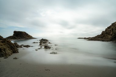 Dalgaların çekildiği kayalık bir koyda küçük bir sahile uzun süre maruz kalmak.