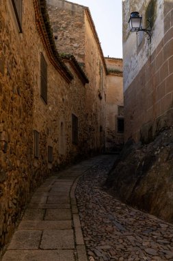 Caceres, İspanya - 30 Mart 2022: Eski şehir merkezi Caceres 'deki tarihi eski binalardan geçen dar kaldırım taşı caddesi