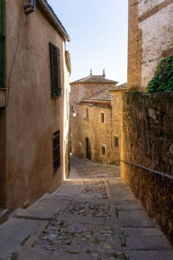 Caceres, İspanya - 30 Mart 2022: Eski şehir merkezi Caceres 'deki tarihi eski binalardan geçen dar kaldırım taşı caddesi