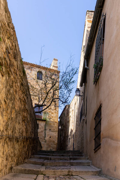 Caceres, Spain - 30 March, 2022: narrow pedestrian cobblestone street leading through the historic old buildings in the Old Town city center of Caceres