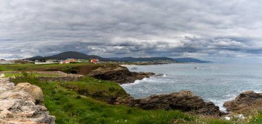 Foz, İspanya - 21 Nisan 2022: Foz yakınlarındaki Galiçya kıyı şeridi yeşil çayırlar ve deniz kıyısındaki evler