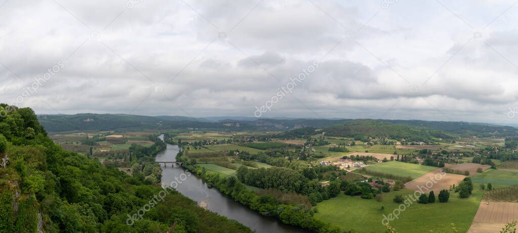 A panorama view of the picturesque Dordogne Valley with river and bridge in dense green summer forest