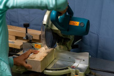 Bir kadın marangoz testereyle odun kesiyor.