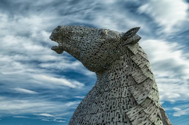 Falkirk, Birleşik Krallık - 20 Haziran 2022: Kelpies at başı heykellerinden biri arkasında anlamlı uzun pozlama gökyüzü ile
