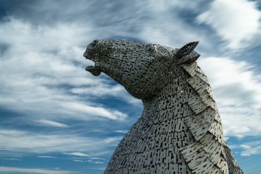 Falkirk, Birleşik Krallık - 20 Haziran 2022: Kelpies at başı heykellerinden biri arkasında anlamlı uzun pozlama gökyüzü ile