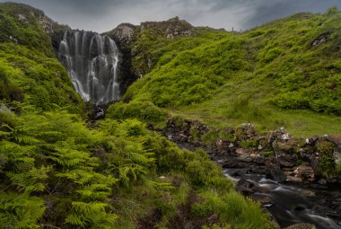 Yaz ortasında İskoçya 'daki Clashniesse Şelalesi manzarası ön planda yemyeşil eğreltiotu