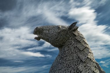 Falkirk, Birleşik Krallık - 20 Haziran 2022: Kelpies at başı heykellerinden biri arkasında anlamlı uzun pozlama gökyüzü ile