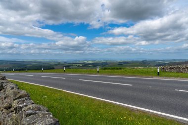 A hilltop view of a highway in the Scottish countryside with a view of the Scottish Borders region