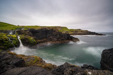 Resimli İrlanda kıyıları ve yazın Dunseverick şelalesinin uzun pozlama manzarası