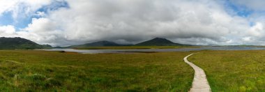 panorama landscape of the Claggan Mountain Coastal Trail bog and boardwalk with the Nephir mountain range in the background