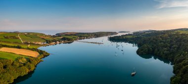 An aerial panorama landscape in warm evening light over Castlehaven Bay with many sailboats anchored