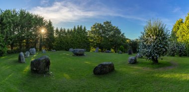 Kenmare, Ireland - 9 August, 2022: panorama landscape of the Kenmare Standing Stones and Wishing Tree in warm evening light with a sunburst