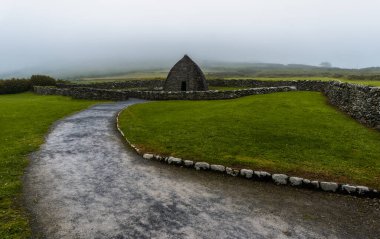 A landscape view of the Gallarus Oratory early-Christian church in County Kerry on a foggy morning