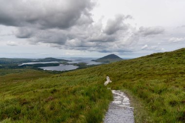 the hiking trail descending from Diamond Hill mountain peak in Connemara National Park with a view of the coast and Kingstown Peninusla