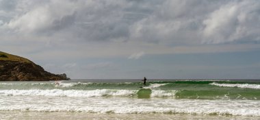 Newquay, Birleşik Krallık - 4 Haziran 2022: Newquay 'da Fistral Sahili' nin panorama manzarası sörfçülerin güneşli bir yaz günü dalgaları yakaladıkları yer.