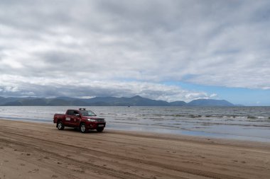 Inch Strand, İrlanda - 5 Ağustos 2022: Batı İrlanda 'da Strand sahilinde kırmızı cankurtaran kamyonu sürüyor.