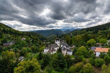 Spania Dolina, Slovakya - 28 Eylül 2022: İspanya 'daki köy ve Roma Katolik Kilisesi manzaralı yeşil yaz ormanı