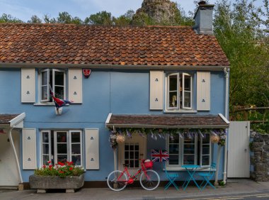 Çedar, Birleşik Krallık - 1 Eylül 2022: kırmızı bisikletli ve İngiliz bayrağı taşıyan köy merkezindeki pitoresk ev