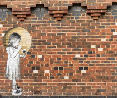 Winchester, İngiltere - 8 Eylül 2022: Üzerinde çiçek tutan küçük bir kızın duvar yazısı olan kırmızı tuğla duvar
