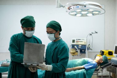 Doktor asistanı olan doktorlar ya da cerrahlar zor ameliyatlar yapmadan önce bir hasta vakası hakkında konuşmak için ameliyathanede duruyorlar..