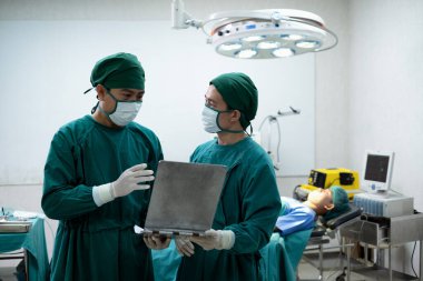 Doktor asistanı olan doktorlar ya da cerrahlar zor ameliyatlar yapmadan önce bir hasta vakası hakkında konuşmak için ameliyathanede duruyorlar..