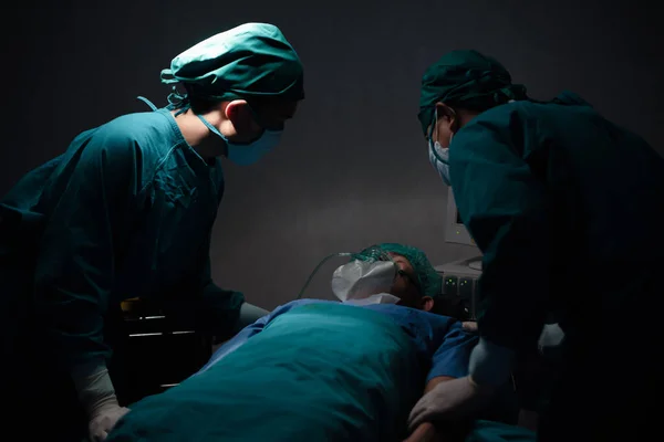 Patient wear a medical ventilator lying on the surgical bed in the operating room with surgeon stand by his side to keep an eye on the symptoms at hospital.