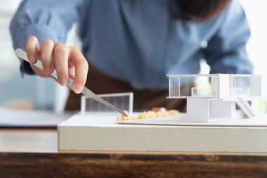 Mimarların eli kapalıyken kadınlar mimarlık atölyesinde, mimarlık tasarımında ya da mimarlık öğrencisi konseptinde modern ev modelini taklit etmek için forseps kullanırlar.