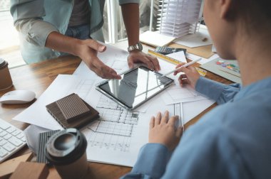Mimarlar ve iç mimarlar kadın tasarımcılar bina tasarımı kavramını tartışıyorlar. Tablet teknolojisi, çizim, materyal ve modelli inşaat projesi tahminleri. Seçici odak merkezi resmi