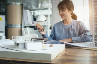 Masanın üzerinde tasarlanmış mimar kadınların modern ev yapımı modeli tasarım işlerinde malzeme örneği ve planlara sahipti..