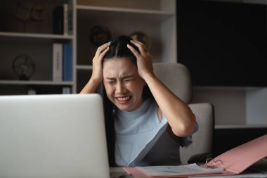 Uzun saçlı iş kadını toplantı odasında çalışma masasına oturur. Önünde çalışmak için dizüstü bilgisayar kullanır. Pembe dosyada bir bilgi işi ayrıntıları var.