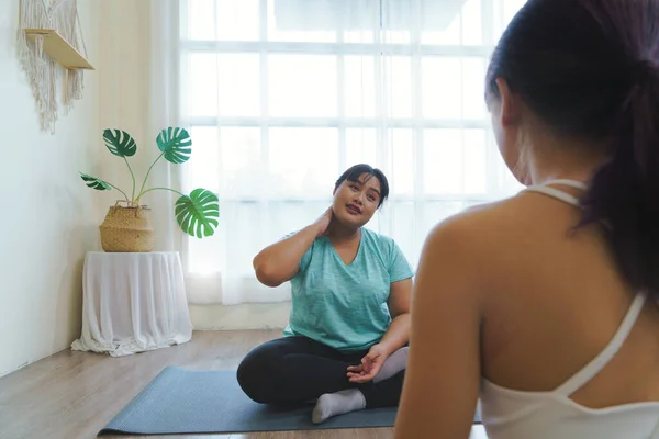 Fat woman good mood sits and talks with a private yoga teacher. feels relaxed after practicing yoga, flexible body. Yoga teacher help guide on how to yoga for obese women or overweight people.