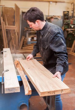 Marangoz, marangozluk atölyesinde sabit dairesel testere tahtasını kesiyor.