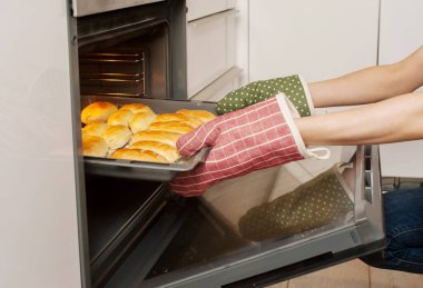 Bir kadın mutfaktaki fırından hazır turtaları yakın plan çeker.