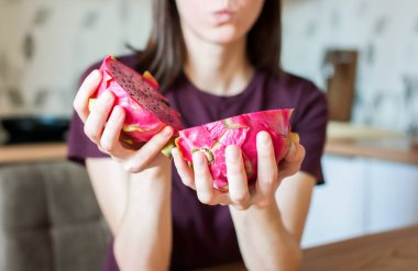 Kız elinde bir ejderha meyveli pitahaya tutuyor. Mutfağa yakın çekim yapıyor. yumuşak odak