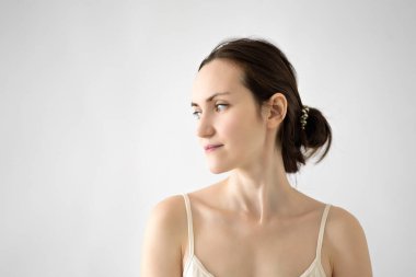 Esmer bir kadının özgün portresi, bej tişörtlü, beyaz arka planda yan yana duran, makyajsız yorgun bir anne, kopyalama alanı.