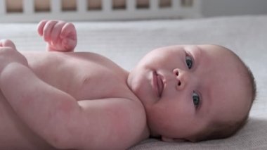 Yeni doğmuş erkek bebek yatakta uzanıyor ve gülümsüyor..