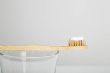 Beyaz arka planda ahşap diş fırçası, camda bambu diş fırçası.