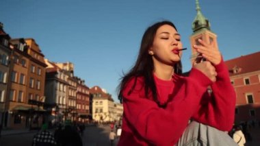 Genç güzel Asyalı kız sokakta sigara içiyor, kırmızı kazak ve kırmızı gül, modern, Varşova Polonya