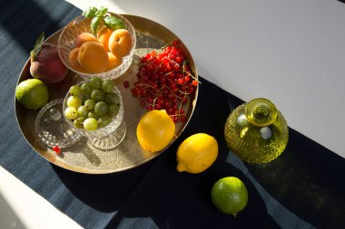 Böğürtlen, üzümler, üzümler, üzümler, limon, limon, portakal, kayısı. Mevsimlik yerel böğürtlen ve meyvelerin bir karışımı eski bir cam tabak ve bir altın antika tepside bulunur.