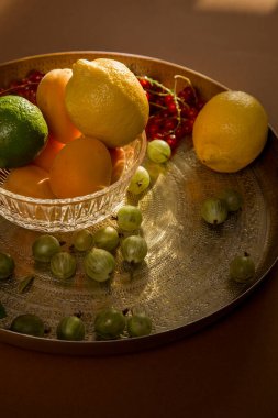 Böğürtlen, üzümler, üzümler, üzümler, limon, limon, portakal, kayısı. Mevsimlik yerel böğürtlen ve meyvelerin bir karışımı eski bir cam tabak ve bir altın antika tepside bulunur.