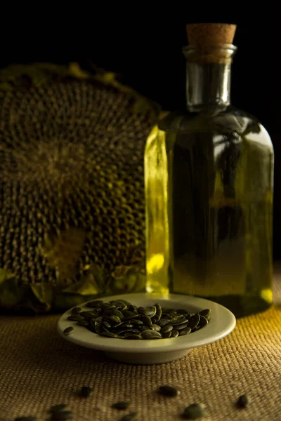 ひまわり ひまわりの種 ひまわり油 油生産 ひまわり油のガラス瓶がテーブルの上にあり 木の背景 バギーテーブルクロス — ストック写真