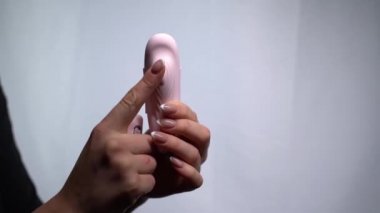 Beyaz arka planda pembe vibro mermileri tutan kadın elleri.