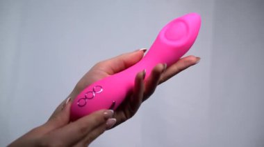 Beyaz arka planda pembe vibratör tutan kadın elleri