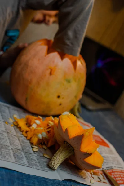 Child carves from a pumpkin. family fun activity. arved pumpkins into jack-o-lanterns for halloween. Carving big orange pumpkins for Halloween in late Autumn.